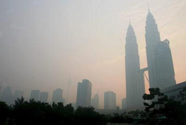 Afbeelding: De beroemde Petronas Towers in Kuala Lumpur achter een dikke smoglaag."
