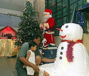 Image: All you want for Xmas: Alvin Hendricks, 31, showing his one-year-old son Chad Victor Hendricks the snowman in his house porch. The snowman shares the space with Santa, a Christmas tree and a Nativity scene."