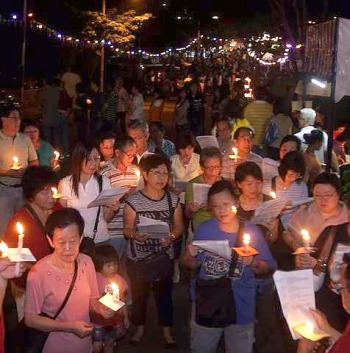 Image: Pilgrims singing hymns while holding lit candles."