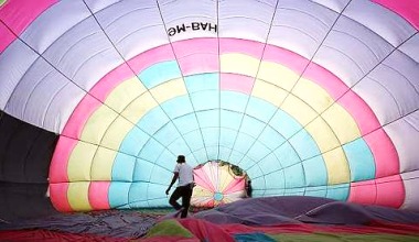 Image: A worker smoothing out the kinks in the canvas for one of the hot-air balloons."